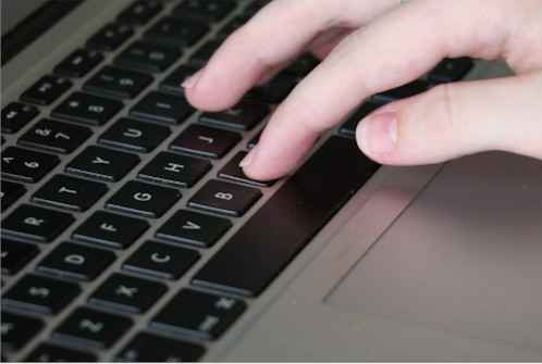 A close-up photograph of a hand typing on a keyboard.